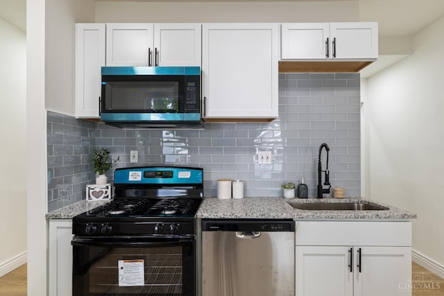 926 Shuler Ave, Hamilton, OH 45011 - kitchen with stainless steel appliances, a sink, white cabinets, light stone counters, and backsplash