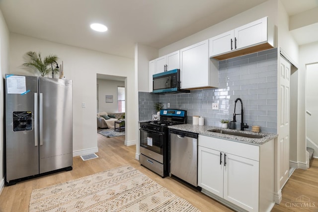 926 Shuler Ave, Hamilton, OH 45011 - kitchen featuring stainless steel appliances, a sink, white cabinetry, and light wood-style flooring