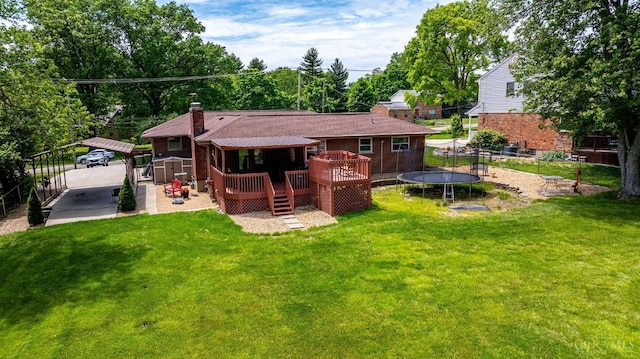 1366 Devils Backbone Rd, Green Twp, OH 45233 - rear view of property featuring a deck, a trampoline, a detached carport, a chimney, and brick siding