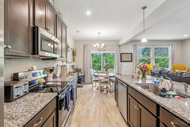 5859 Parkview Ln, Miami Twp, OH 45150 - kitchen with appliances with stainless steel finishes, light wood finished floors, pendant lighting, dark brown cabinetry, and a chandelier