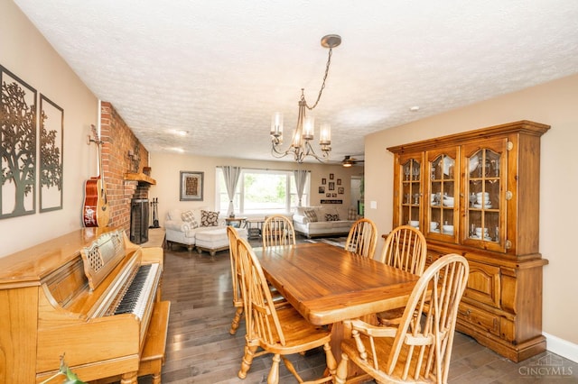 6290 Ludlum Rd, Salem Twp, OH 45152 - dining room featuring a textured ceiling, a chandelier, a brick fireplace, and dark wood finished floors