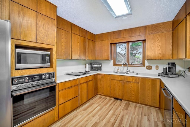 4723 Rosedale Rd, Middletown, OH 45042 - kitchen with stainless steel appliances, a sink, a textured ceiling, light countertops, and light wood finished floors