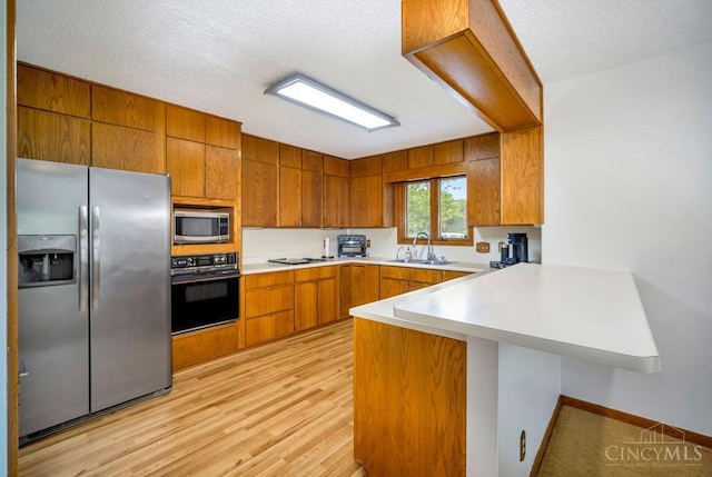 4723 Rosedale Rd, Middletown, OH 45042 - kitchen featuring appliances with stainless steel finishes, a peninsula, a sink, brown cabinets, and light countertops