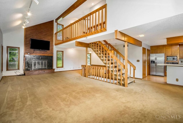 4723 Rosedale Rd, Middletown, OH 45042 - unfurnished living room featuring high vaulted ceiling, light carpet, a large fireplace, rail lighting, and stairway
