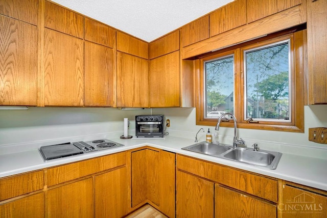 4723 Rosedale Rd, Middletown, OH 45042 - kitchen featuring a sink, light countertops, stovetop with downdraft, brown cabinets, and a textured ceiling