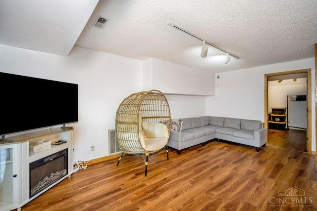 4723 Rosedale Rd, Middletown, OH 45042 - living room with track lighting, wood finished floors, a textured ceiling, and a fireplace