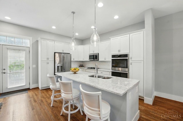 9276 Beacon St, Deerfield Twp, OH 45040 - kitchen featuring appliances with stainless steel finishes, a sink, backsplash, white cabinets, and a center island with sink
