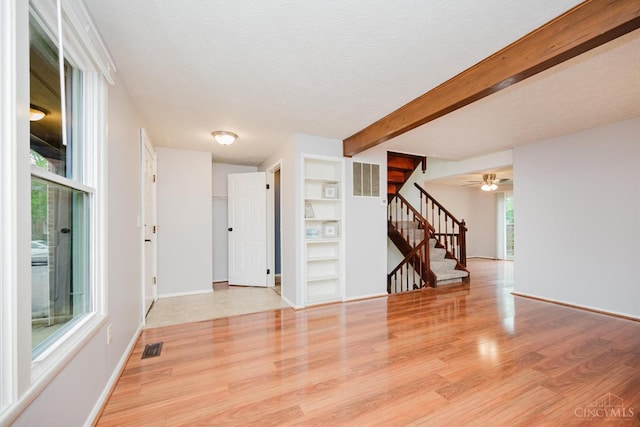 4634 Courtwood Cir, Union Twp, OH 45103 - empty room featuring stairs, light wood-style floors, baseboards, built in shelves, and beam ceiling
