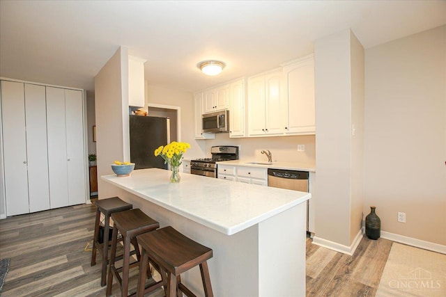 2324 Madison Rd Unit 506, Cincinnati, OH 45208 - kitchen with stainless steel appliances, wood finished floors, a breakfast bar, white cabinetry, and baseboards