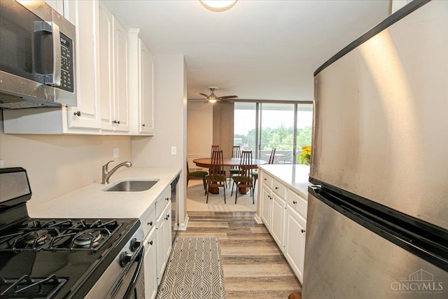 2324 Madison Rd Unit 506, Cincinnati, OH 45208 - kitchen featuring appliances with stainless steel finishes, a sink, light wood-type flooring, white cabinets, and expansive windows