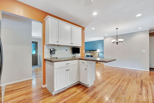 8714 Wuest Rd, Colerain Twp, OH 45251 - kitchen featuring light wood finished floors, a peninsula, tasteful backsplash, white cabinets, and a chandelier