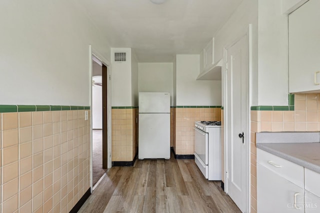 3366 Wunder Ave, Cincinnati, OH 45211 - kitchen featuring white appliances, tile walls, wainscoting, wood finished floors, and white cabinetry