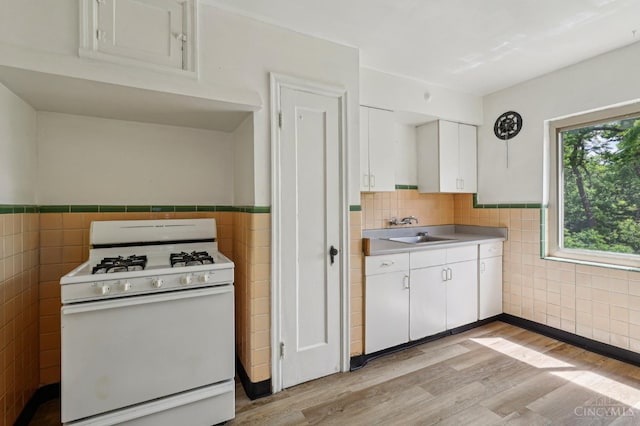 3366 Wunder Ave, Cincinnati, OH 45211 - kitchen featuring white gas range oven, tile walls, white cabinetry, light wood-style floors, and a sink