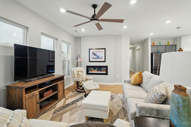 5014 S Castle Ct, Liberty Twp, OH 45011 - living room featuring a ceiling fan, light wood-style flooring, a glass covered fireplace, recessed lighting, and baseboards