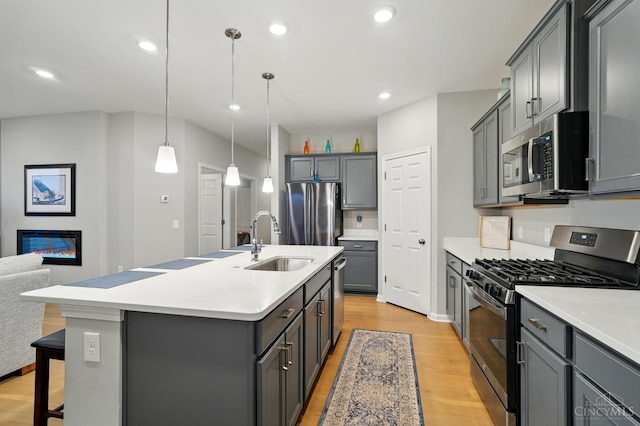 5014 S Castle Ct, Liberty Twp, OH 45011 - kitchen with appliances with stainless steel finishes, a sink, light wood-style flooring, gray cabinetry, and a kitchen breakfast bar
