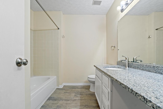 2020 Woodcreek Dr, Fairfield, OH 45014 - bathroom featuring toilet, a textured ceiling, vanity, wood finished floors, and bathtub / shower combination