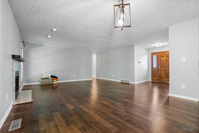2020 Woodcreek Dr, Fairfield, OH 45014 - unfurnished living room featuring a textured ceiling, a fireplace with raised hearth, wood finished floors, and baseboards