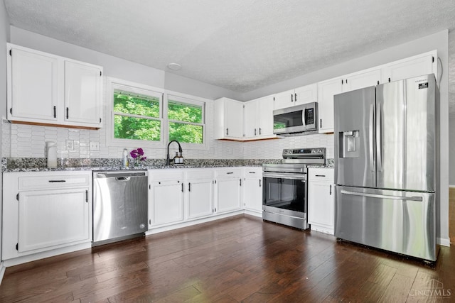 2020 Woodcreek Dr, Fairfield, OH 45014 - kitchen with stainless steel appliances, dark stone countertops, a sink, white cabinets, and dark wood finished floors