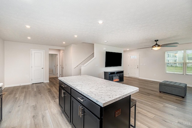 6482 Tralee Ln, Goshen Twp, OH 45122 - kitchen featuring a center island, light wood finished floors, ceiling fan, light countertops, and baseboards
