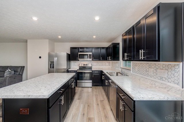 6482 Tralee Ln, Goshen Twp, OH 45122 - kitchen featuring stainless steel appliances, a sink, dark cabinetry, a center island, and a textured ceiling