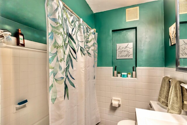5411 Lester Rd, Cincinnati, OH 45213 - bathroom featuring tile walls, toilet, vanity, shower / bath combination with curtain, and a wainscoted wall