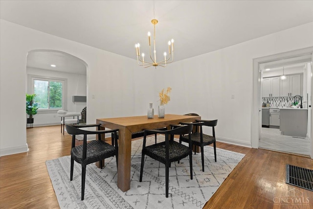 3970 Abington Ave, Cincinnati, OH 45229 - dining space featuring arched walkways, light wood-style flooring, and a chandelier