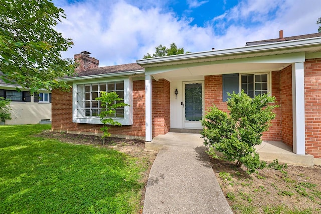 1885 Forest View Ct, Green Twp, OH 45233 - property entrance with a chimney, a lawn, brick siding, and covered porch