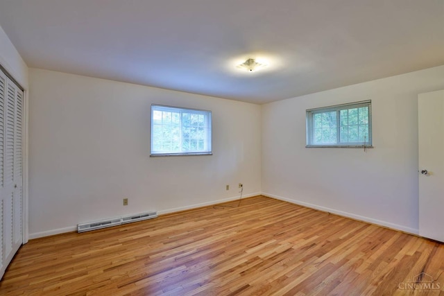 1885 Forest View Ct, Green Twp, OH 45233 - unfurnished bedroom featuring light wood finished floors, multiple windows, a baseboard radiator, and baseboards