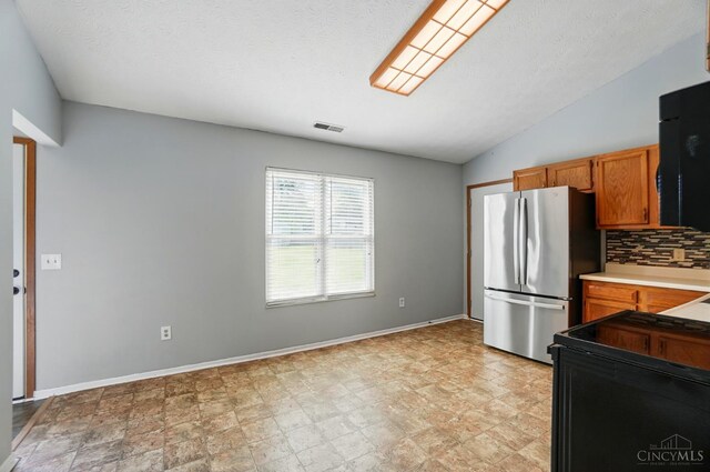 3914 Brookville Dr, Batavia Twp, OH 45102 - kitchen featuring freestanding refrigerator, backsplash, baseboards, brown cabinets, and black / electric stove