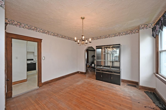 1917 Webman Ct, Cincinnati, OH 45223 - unfurnished dining area featuring light wood finished floors, a textured ceiling, arched walkways, a chandelier, and baseboards