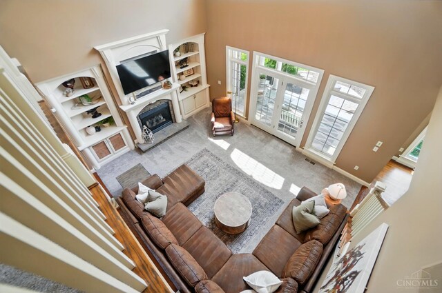 7757 Misty Meadows Ct, Harlan Twp, OH 45152 - living area featuring a towering ceiling, light carpet, a fireplace with raised hearth, built in features, and baseboards