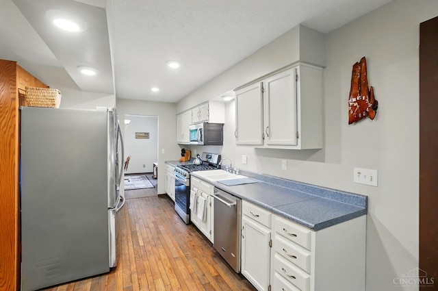 21 Garden Cir, Wilmington, OH 45177 - kitchen with appliances with stainless steel finishes, hardwood / wood-style flooring, white cabinets, recessed lighting, and a sink