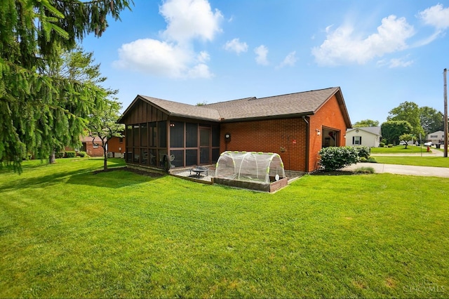 21 Garden Cir, Wilmington, OH 45177 - back of property featuring a sunroom, brick siding, an attached garage, a lawn, and concrete driveway
