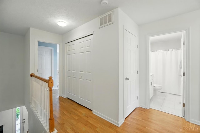 943 Steamboat Dr Unit 204, Union Twp, OH 45244 - hall featuring an upstairs landing, light wood finished floors, baseboards, and a textured ceiling