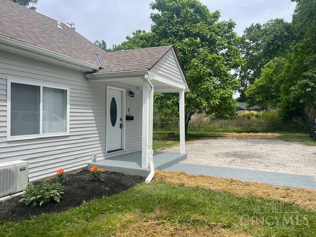 4 Cottage Ct, Anderson Twp, OH 45230 - view of exterior entry featuring a shingled roof, ac unit, and a patio area