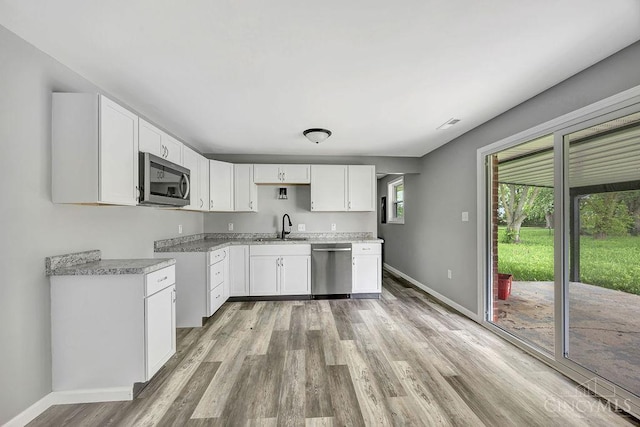 8486 US Route 127, West Manchester, OH 45382 - kitchen with a sink, stainless steel appliances, light wood-type flooring, baseboards, and white cabinetry