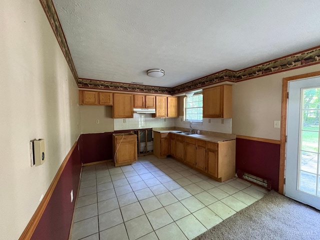 2307 Wilshire Cir, Stonelick Twp, OH 45122 - kitchen with under cabinet range hood, plenty of natural light, brown cabinetry, a textured ceiling, and light tile patterned floors