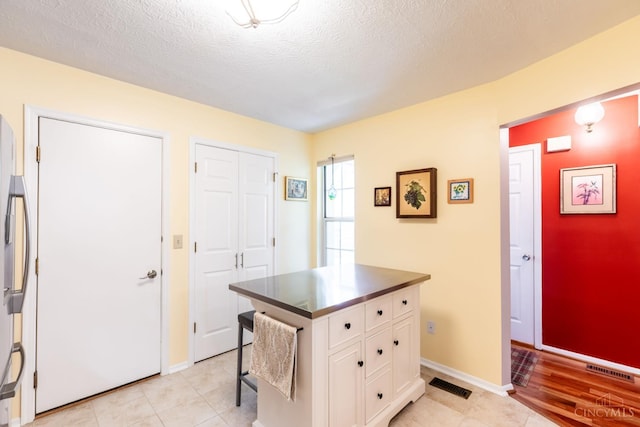 1627 Braintree Dr, Anderson Twp, OH 45255 - kitchen with white cabinetry, dark countertops, baseboards, a textured ceiling, and stainless steel fridge