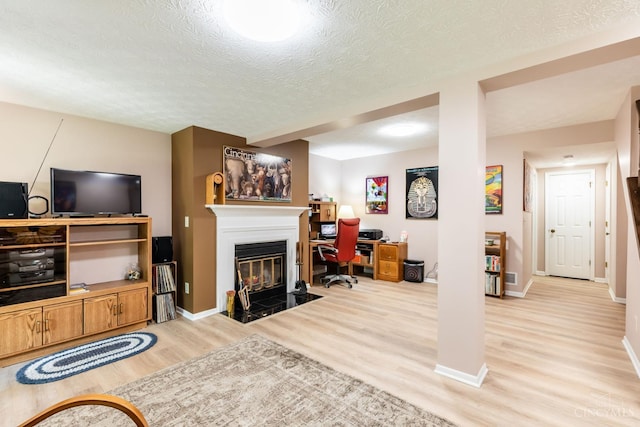 1627 Braintree Dr, Anderson Twp, OH 45255 - living area featuring light wood-type flooring, an office area, a textured ceiling, baseboards, and a fireplace with flush hearth