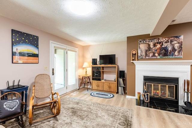 1627 Braintree Dr, Anderson Twp, OH 45255 - living area featuring wood finished floors, a textured ceiling, and a glass covered fireplace