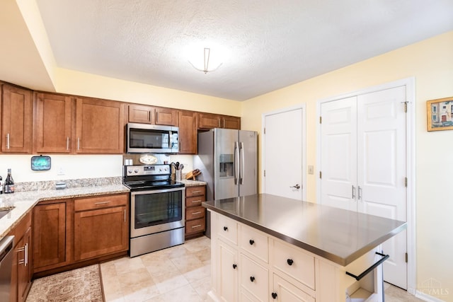 1627 Braintree Dr, Anderson Twp, OH 45255 - kitchen featuring appliances with stainless steel finishes, brown cabinetry, white cabinetry, a textured ceiling, and light stone counters