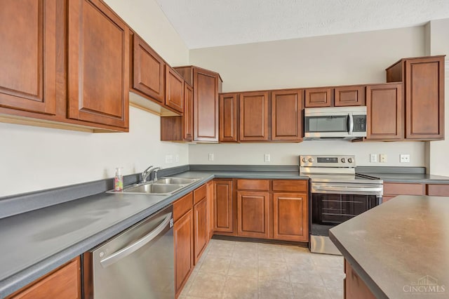 9298 Greenery Ct, Deerfield Twp, OH 45140 - kitchen featuring appliances with stainless steel finishes, a sink, dark countertops, brown cabinetry, and a textured ceiling