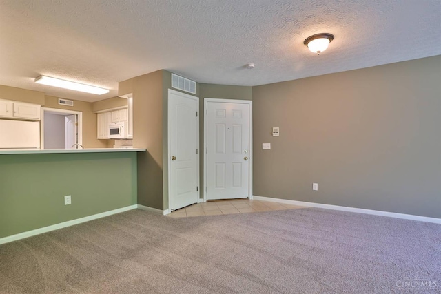 715 Castlegate Ln Unit 102, Springfield Twp, OH 45231 - empty room featuring light carpet, a textured ceiling, baseboards, and light tile patterned flooring