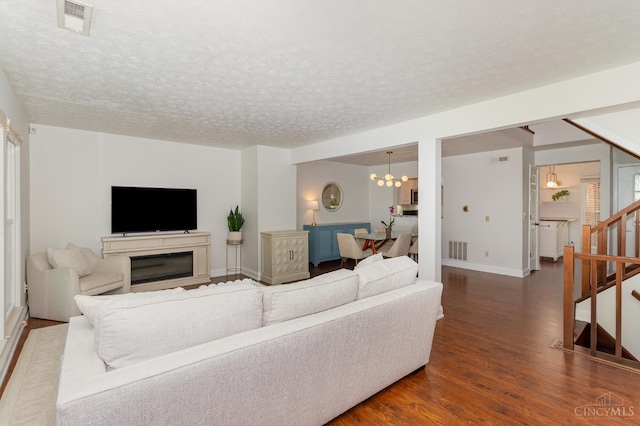 1732 Emerald Glade Ln Unit 6D, Anderson Twp, OH 45255 - living area featuring dark wood-style flooring, stairs, a chandelier, a textured ceiling, and a glass covered fireplace