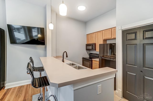 2110 Fulton Ave Unit 3, Cincinnati, OH 45206 - kitchen with black appliances, a sink, a breakfast bar, decorative light fixtures, and baseboards