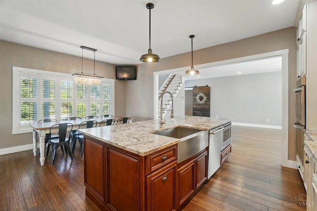 5757 W Fork Rd, Green Twp, OH 45247 - kitchen with a sink, dark wood-style flooring, baseboards, decorative light fixtures, and light stone counters