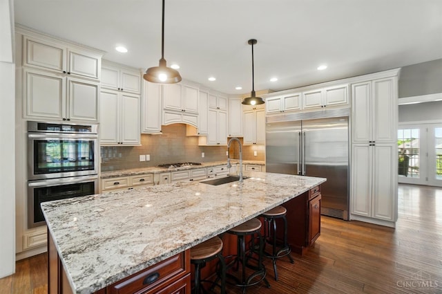 5757 W Fork Rd, Green Twp, OH 45247 - kitchen featuring appliances with stainless steel finishes, a sink, backsplash, dark wood-type flooring, and a kitchen island with sink