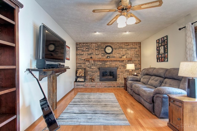 3169 John Gray Rd, Colerain Twp, OH 45251 - living room with a ceiling fan, light wood finished floors, a textured ceiling, and a brick fireplace