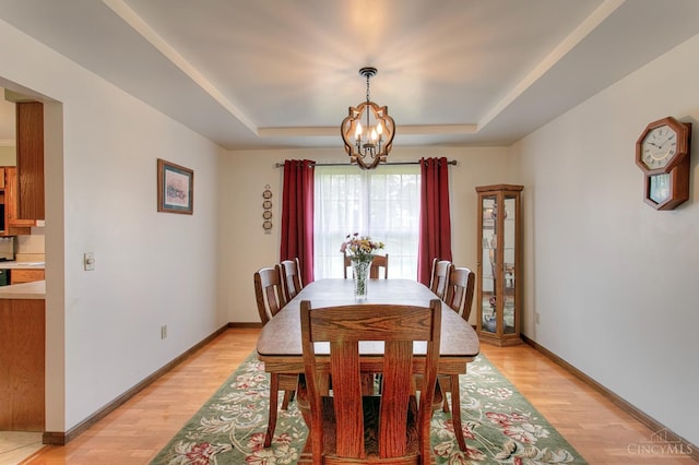 3169 John Gray Rd, Colerain Twp, OH 45251 - dining area with a chandelier, a tray ceiling, light wood-type flooring, and baseboards