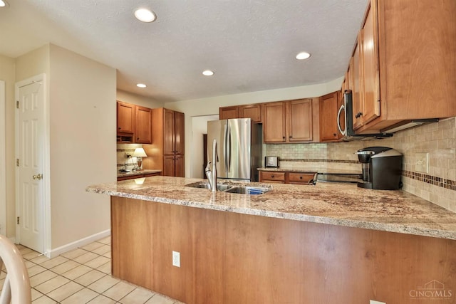 8750 E Kemper Rd, Symmes Twp, OH 45249 - kitchen with stainless steel appliances, brown cabinetry, light stone counters, light tile patterned floors, and tasteful backsplash